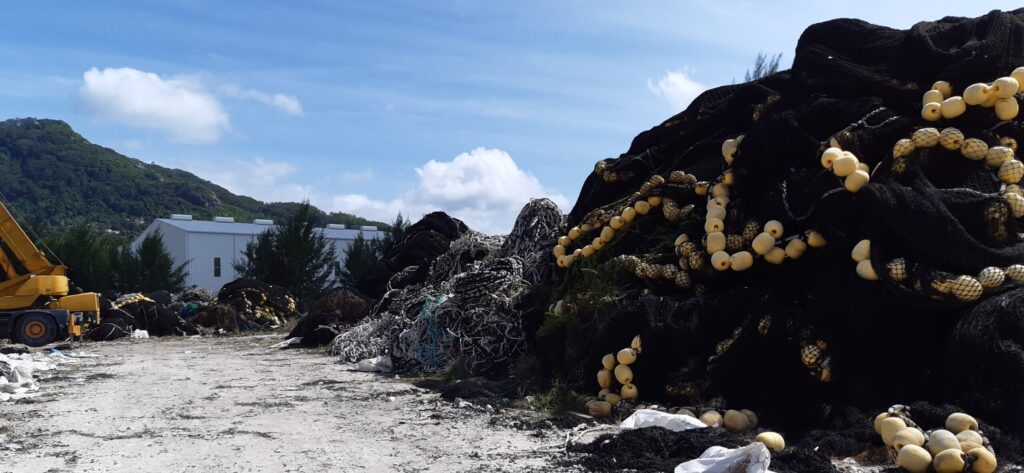 Tall accumulated pile of end-of-life industrial fishing nets and floats at a Seychelles net storage yard